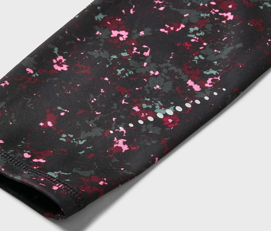 Nahaufnahme eines Ärmels mit einem schwarzen Blumenmuster mit rosa und roten Akzenten und einer Reihe weißer Punkte.