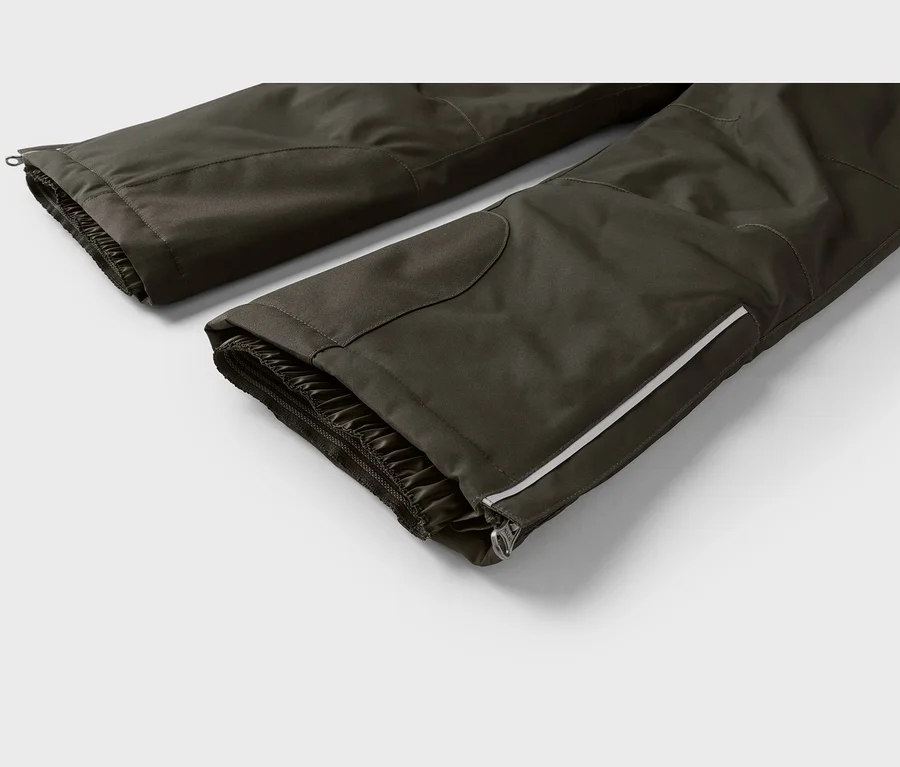 Nahaufnahme von zwei dunkelgrauen Hosenbeinen mit elastischen Innenbündchen. Das vordere Hosenbein hat einen weißen Reflexstreifen und einen Reißverschluss an der Seite.