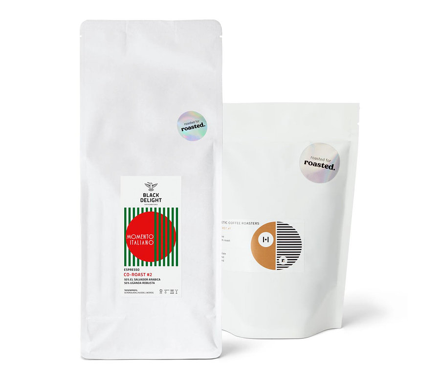 Zwei weiße Kaffeepackungen nebeneinander. Eine Packung ist Espresso Probierpaket "Co-Roast Duo".