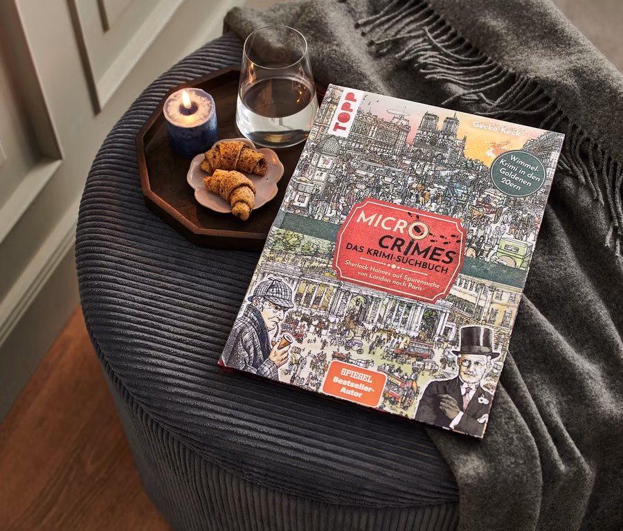 Auf einem Hocker liegen das Buch "Micro Crimes – das Krimi-Suchbuch", ein Glas Wasser, eine Kerze und ein Teller mit Croissants.