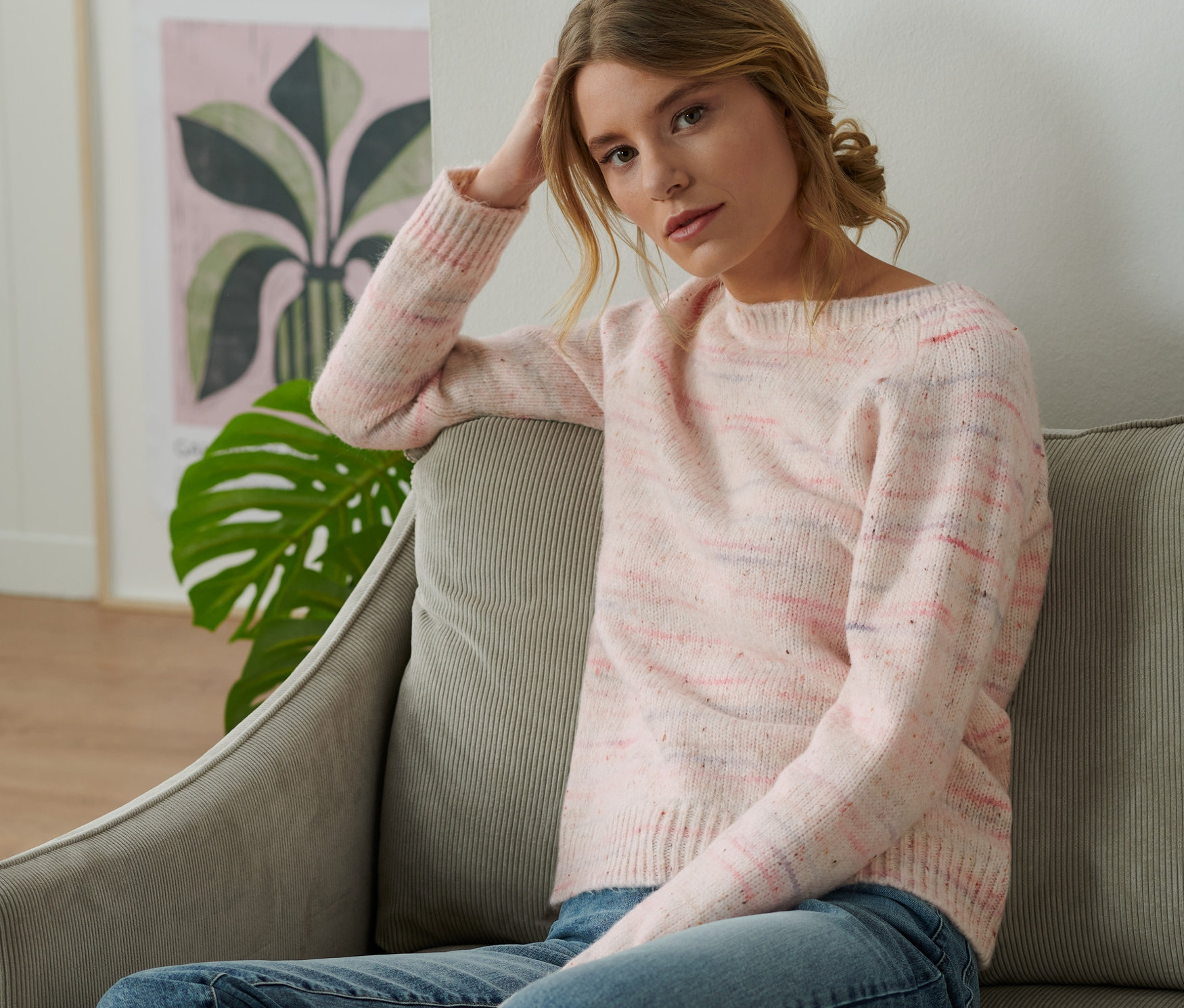 Frau sitzt auf einem Sofa und trägt einen Grobstrick-Pullover mit Effektgarn.