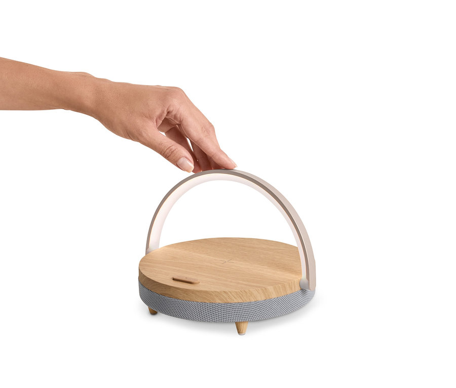 Eine Hand berührt einen Bluetooth-Lautsprecher mit kabellosem Ladegerät und LED-Nachtlicht.