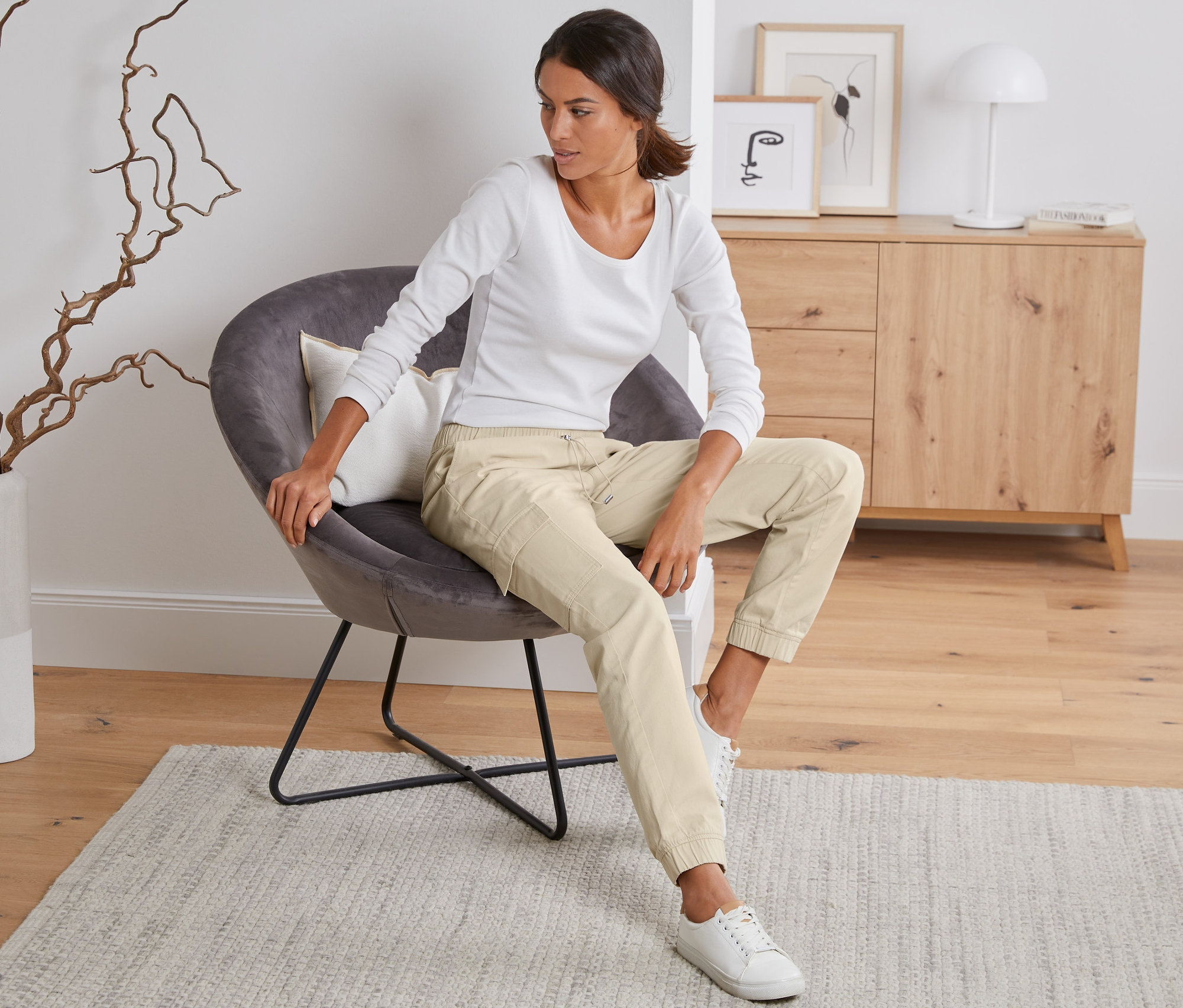 Frau sitzt im Sessel und trägt eine Cargohose.