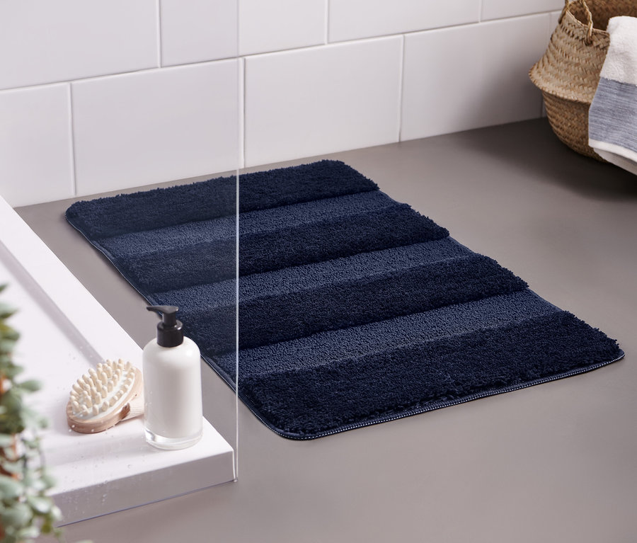 Marineblaue Wellness-Badematte, ca. 50 x 80 cm, liegt auf grauem Boden neben einem Waschbecken.