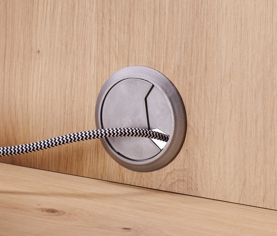 Detail eines Sideboards mit Schubladen und Tür, Kabel durch eine Öffnung geführt.