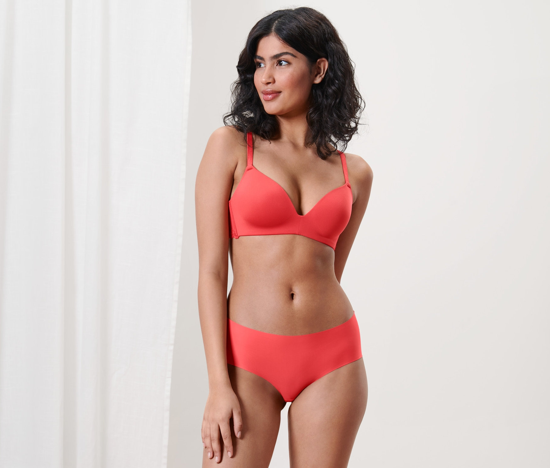 Frau posiert in rotem BH und 2 Magic-Cut-Pantys.