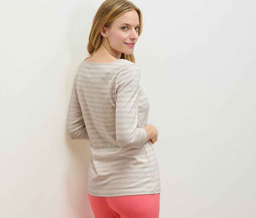 Frau blickt über die Schulter und trägt ein gestreiftes Shirt mit 3/4-Arm.