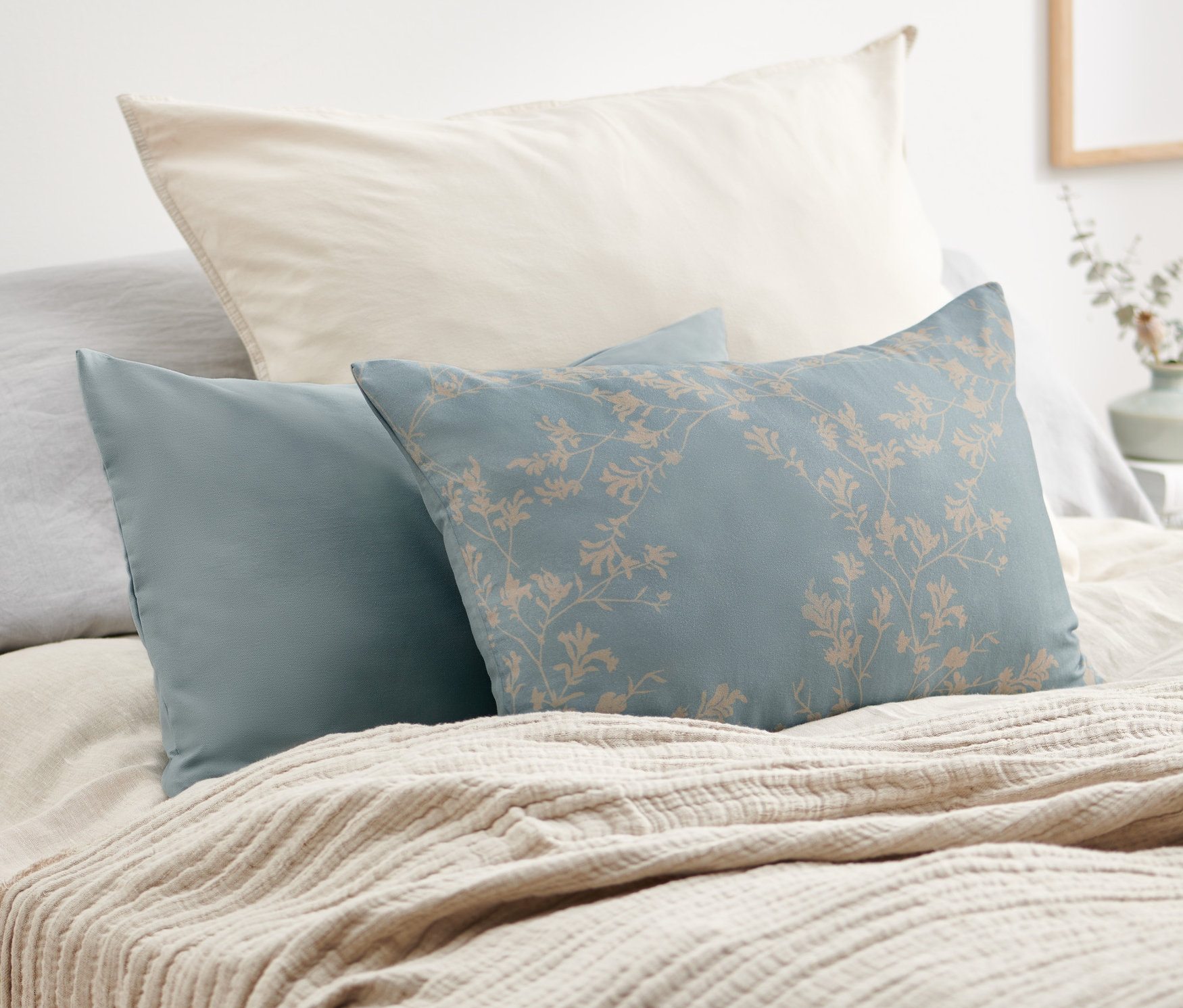 Zwei Dekokissen-Bezüge liegen auf einem Bett.