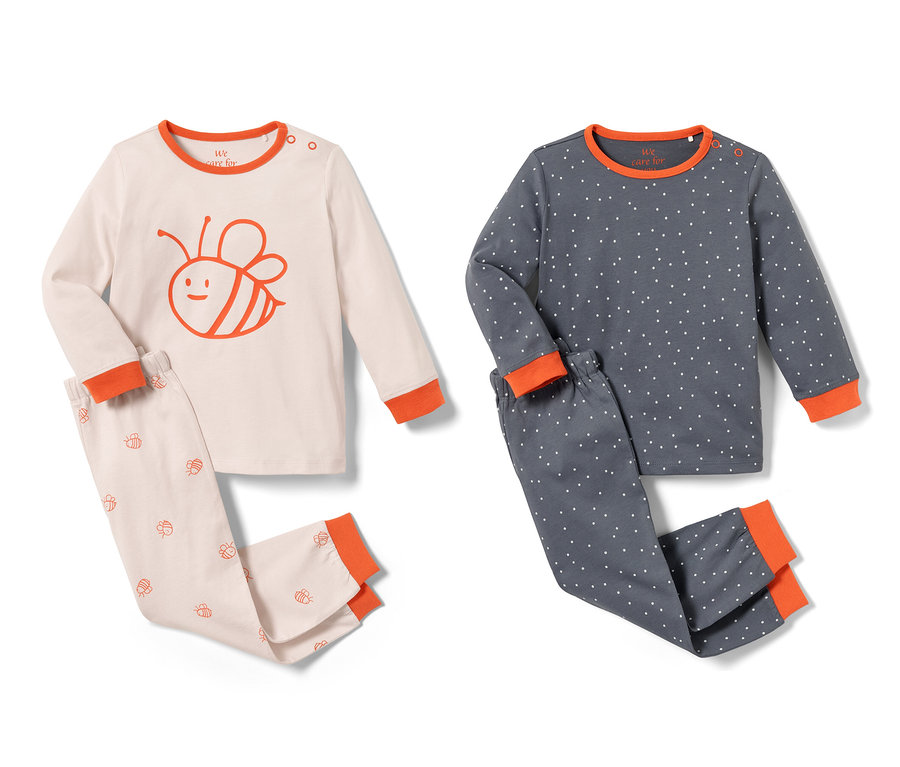Zwei Kleinkinder-Pyjamas, ein rosa Pyjama mit Bienenmuster und ein blauer mit weißen Punkten.