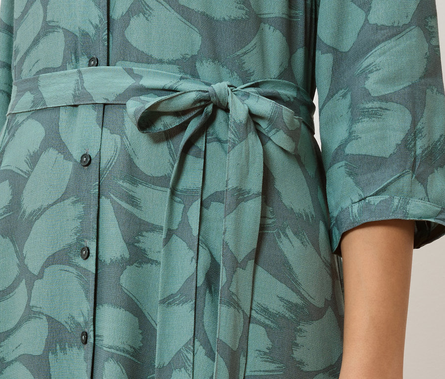 Detail eines türkisfarbenen Hemdblusenkleids mit grauem Pinselstrichmuster und gebundener Taille.