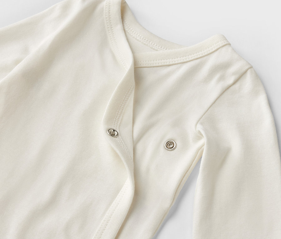 Detailaufnahme eines weißen Baby-Bodys mit langen Ärmeln aus einem 5er-Set mit Mitwachsfunktion.