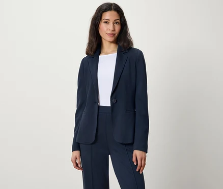 Frau posiert in dunkelblauem Blazer und Hose.