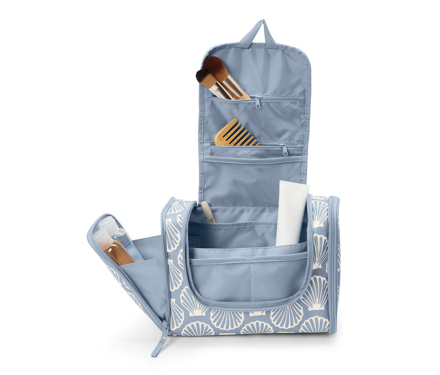 Offene blaue Kulturtasche mit Muschelmuster und diversen Toilettenartikeln.