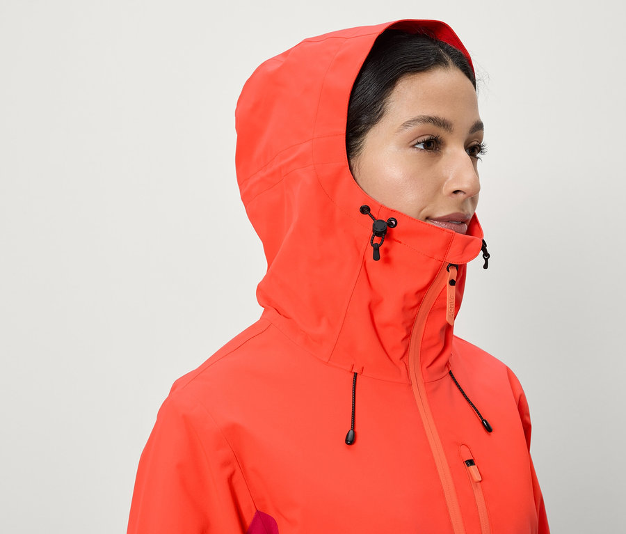 Eine Frau trägt eine korallenrote Jacke mit Kapuze.