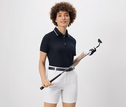 Frau hält Golfschläger und trägt ein dunkelblaues Funktionspoloshirt.