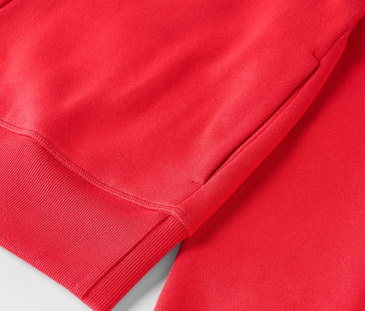 Detailaufnahme eines roten Kapuzenpullovers mit geripptem Saum.