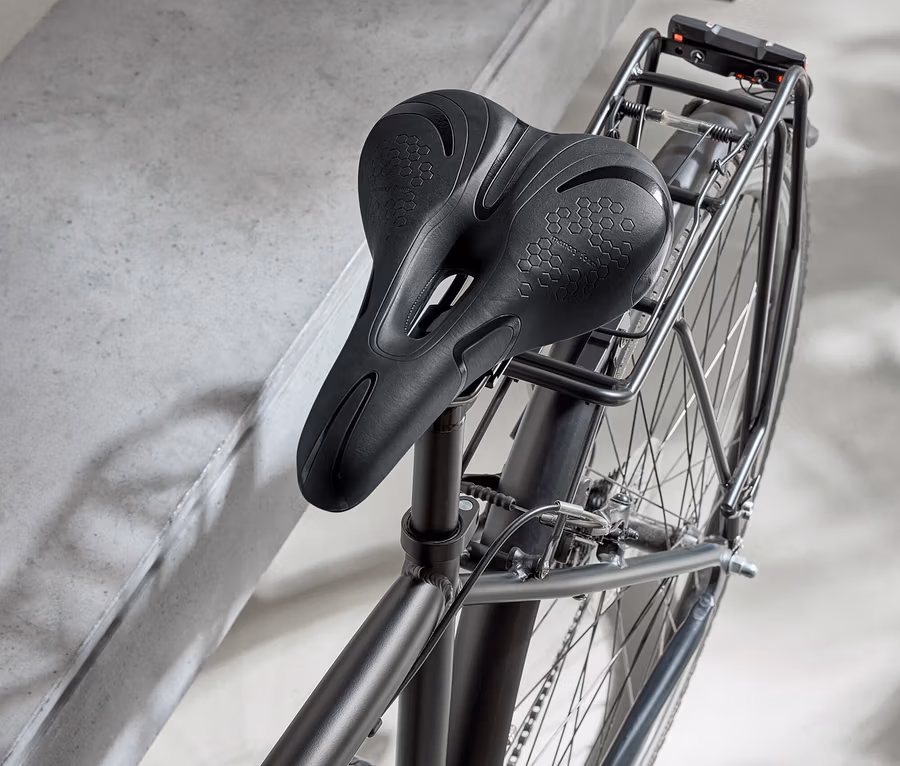 Schwarzes Fahrrad mit schwarzem Sattel und schwarzem Helm auf einer Betonoberfläche.