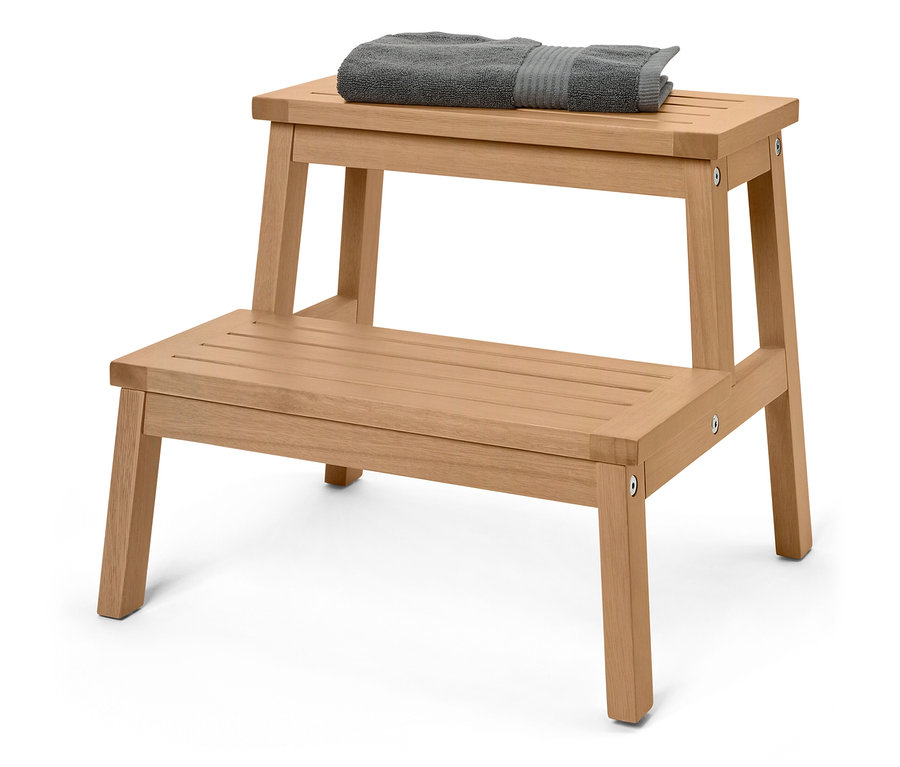 Ein hölzerner Tritthocker mit zwei Stufen, auf der oberen Stufe liegt ein graues Handtuch.