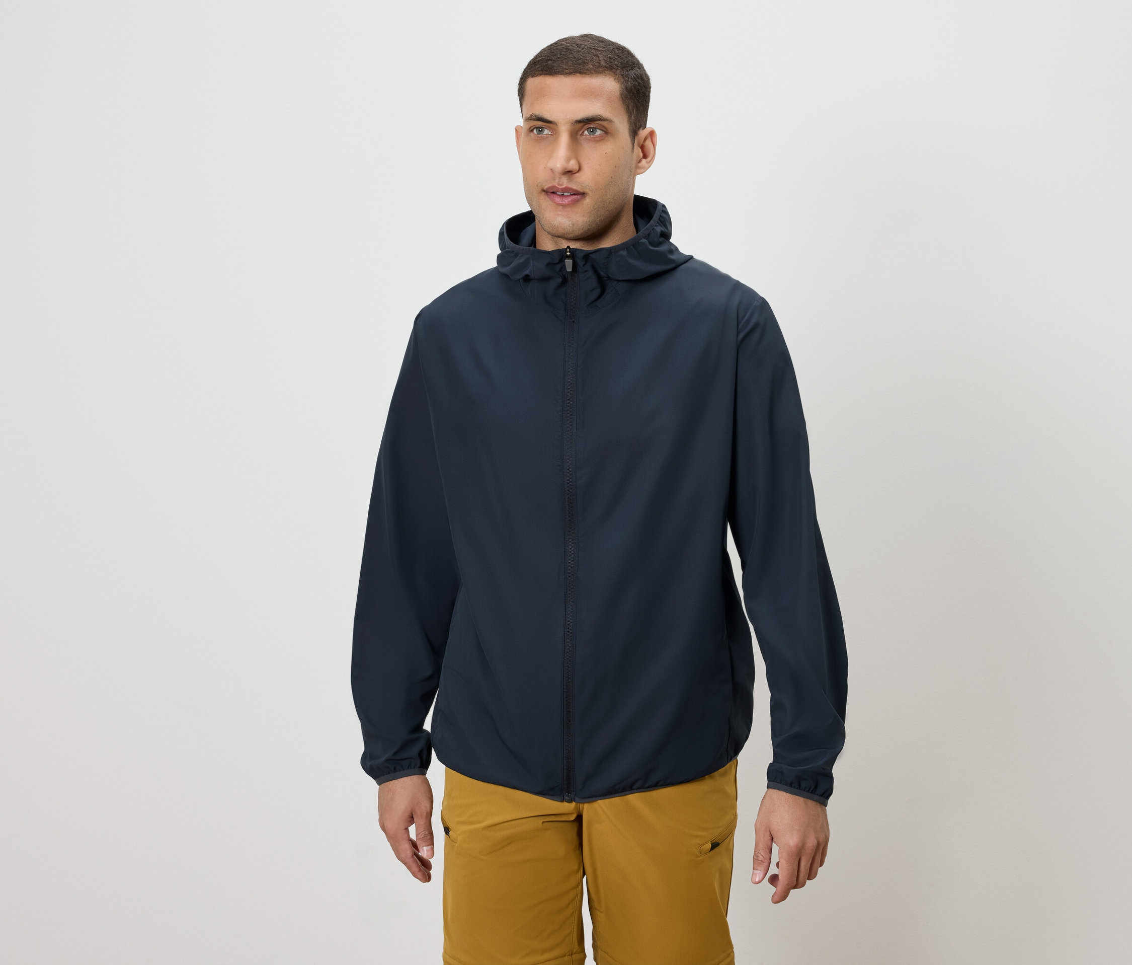 Mann trägt eine marineblaue Kapuzenjacke und goldene Shorts.