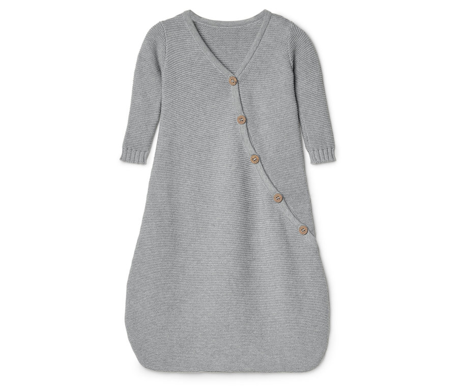 Ein grauer, gestrickter Babyschlafsack mit langen Ärmeln und einer Knopfleiste liegt auf einer weißen Oberfläche.