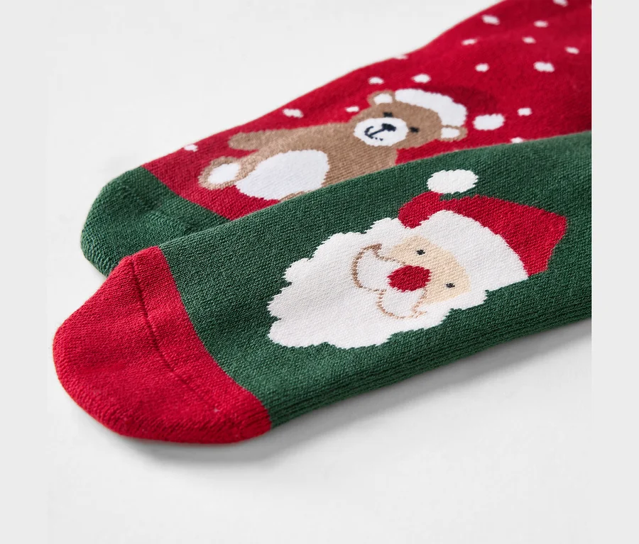 Detailaufnahme von roten und grünen Weihnachtssocken mit Bär und Weihnachtsmann.