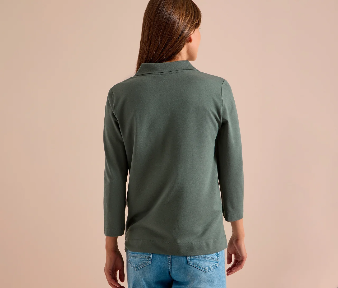 Frau von hinten in grünem CECIL 3/4-Poloshirt und blauer Jeans.