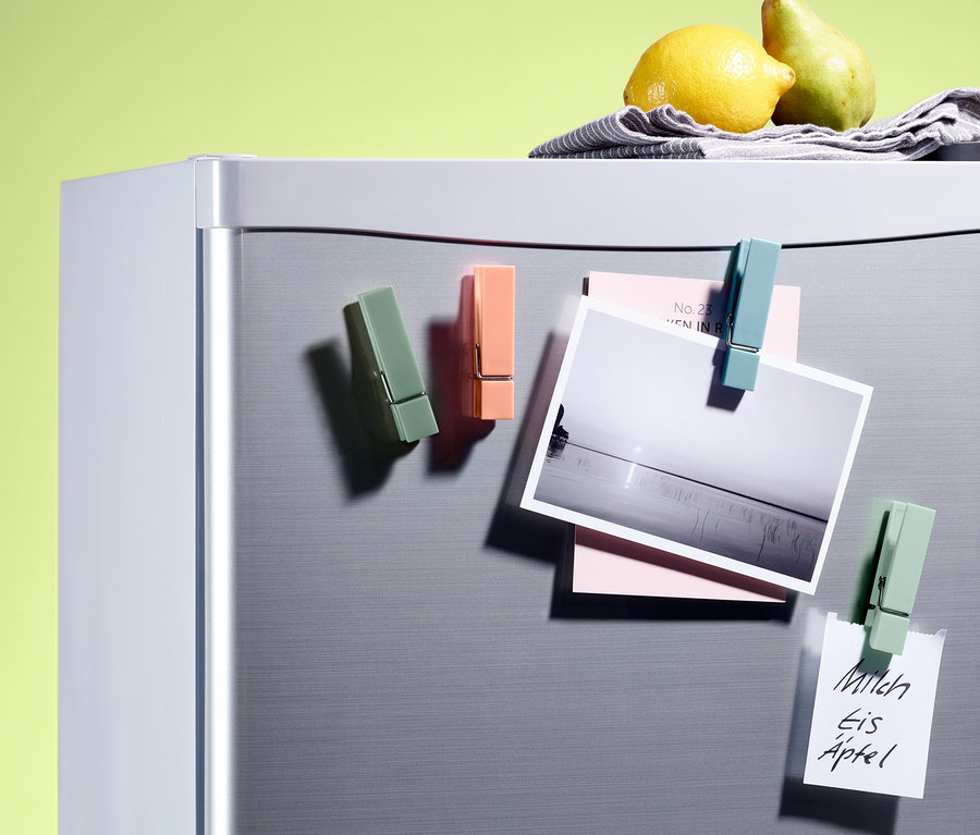 Vier Kühlschrankmagnete befestigen ein Foto und Notizen an einem Kühlschrank.