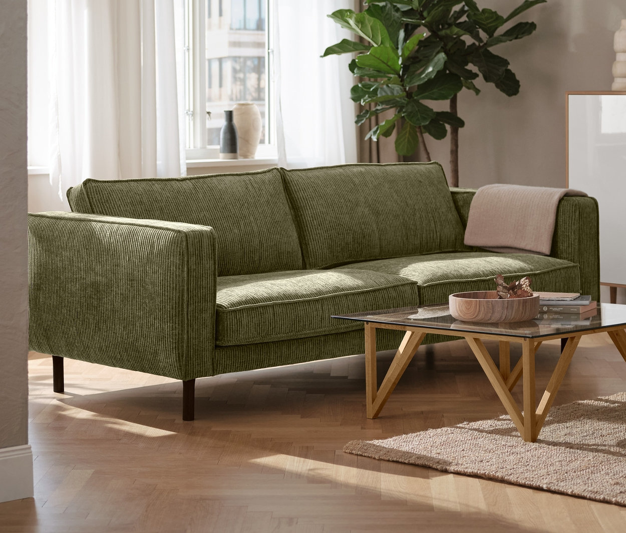 Ein grünes 3-Sitzer-Cordsofa steht im Wohnzimmer, daneben eine schwarze Stehleuchte aus Metall und ein weißes Highboard »Bekeson«.