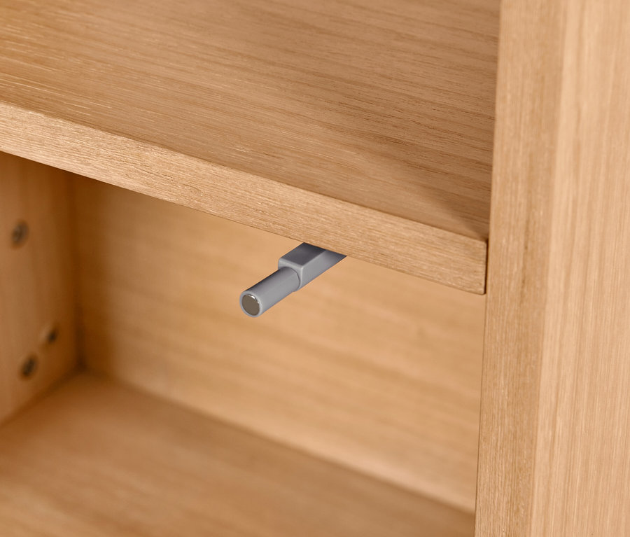 Detailansicht eines Badschranks mit Holzfurnier und grauem Mechanismus.