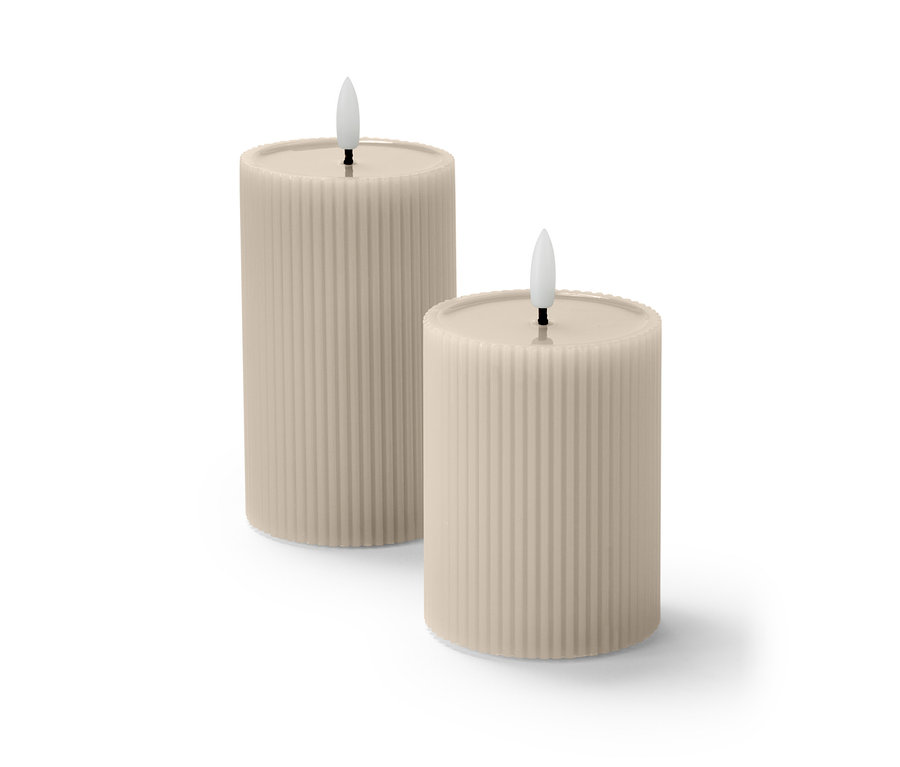 Zwei beigefarbene LED-Kerzen mit Echtwachsspiegel und geriffelter Oberfläche stehen nebeneinander.