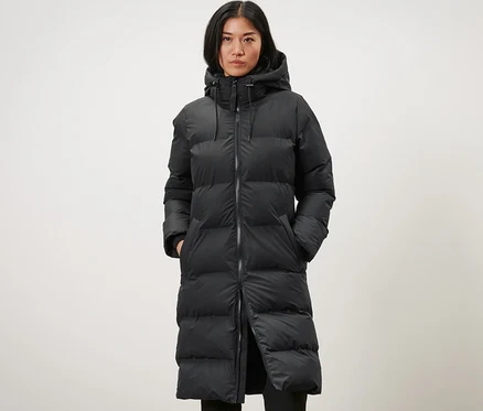 Frau trägt einen langen schwarzen Winter-Regenmantel.