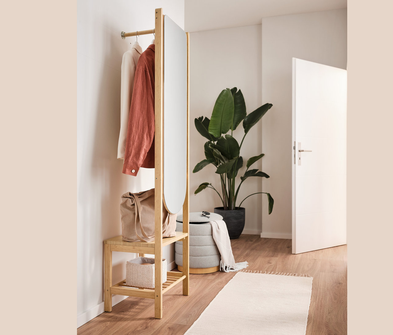 Garderobe mit Spiegel und Ablage, Pouf mit Stauraum, Tasche und Kleidung im Innenraum.