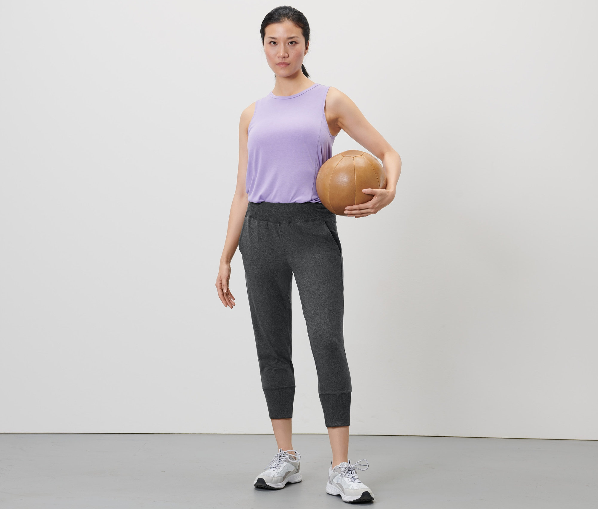 Frau hält einen Basketball und trägt eine 3/4-Sporthose in Anthrazit.