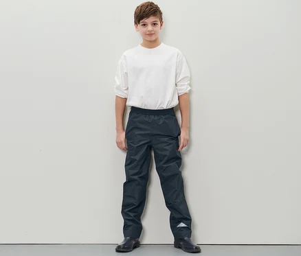 Junge steht und trägt eine Kinder-Regenhose.