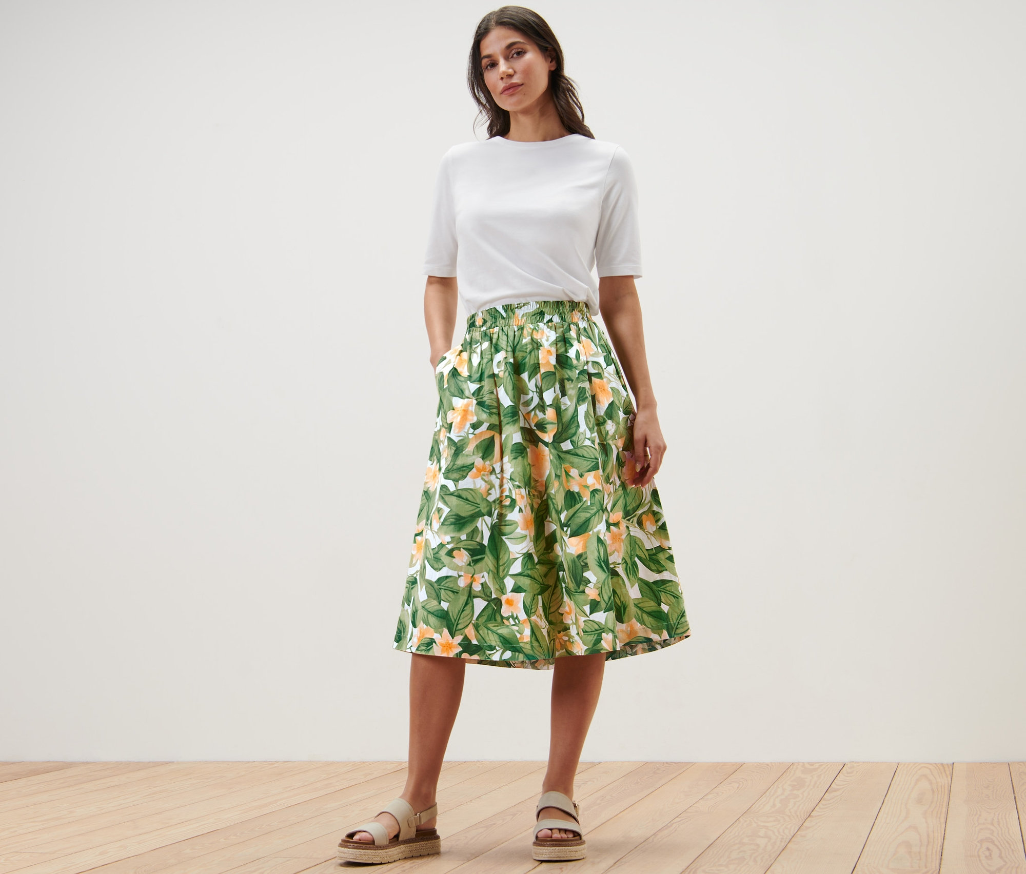 Frau posiert in weißem T-Shirt und bedrucktem Popeline-Rock.