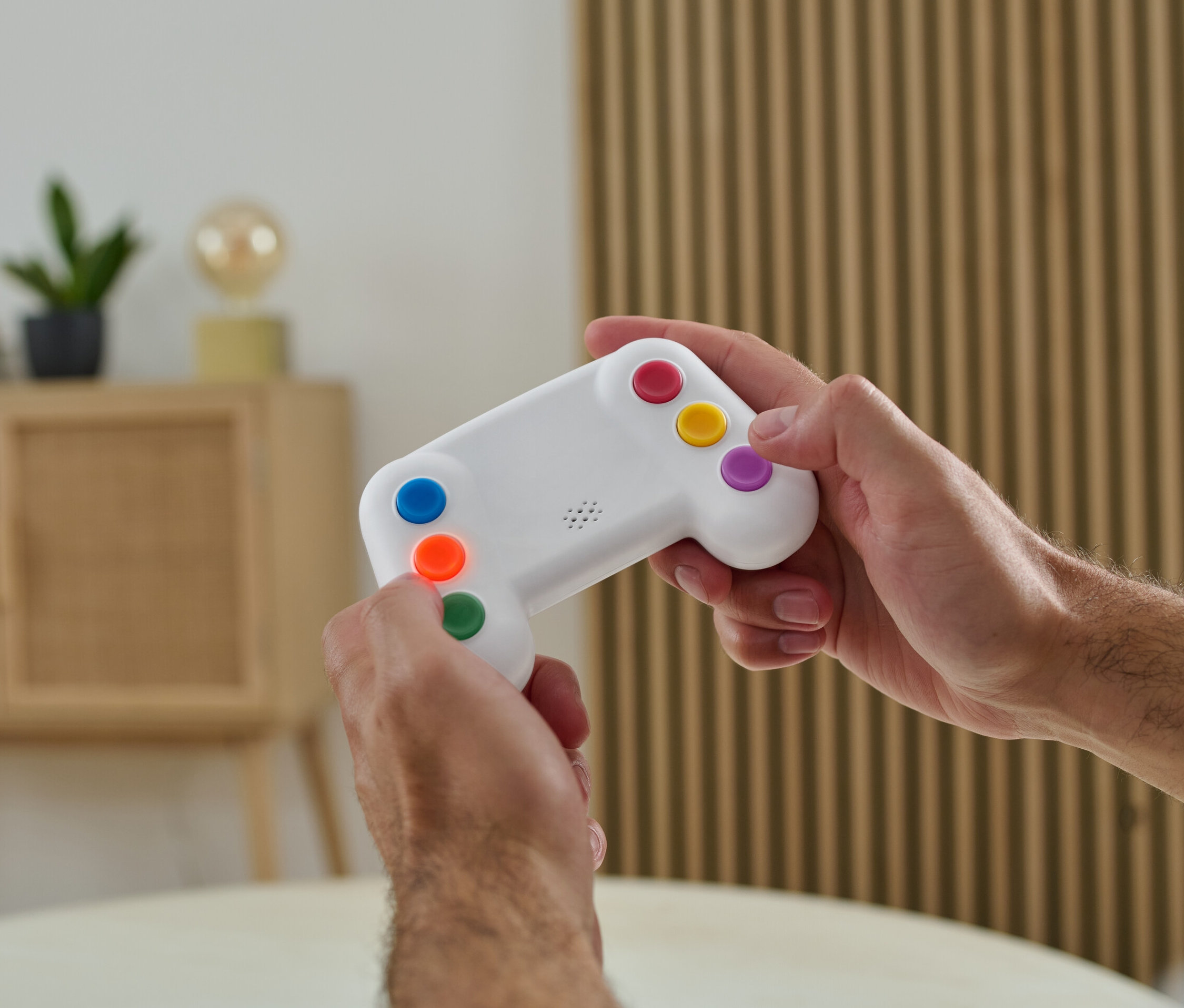 Mann hält einen elektronischen Gedächtnistrainer mit bunten Knöpfen in den Händen.