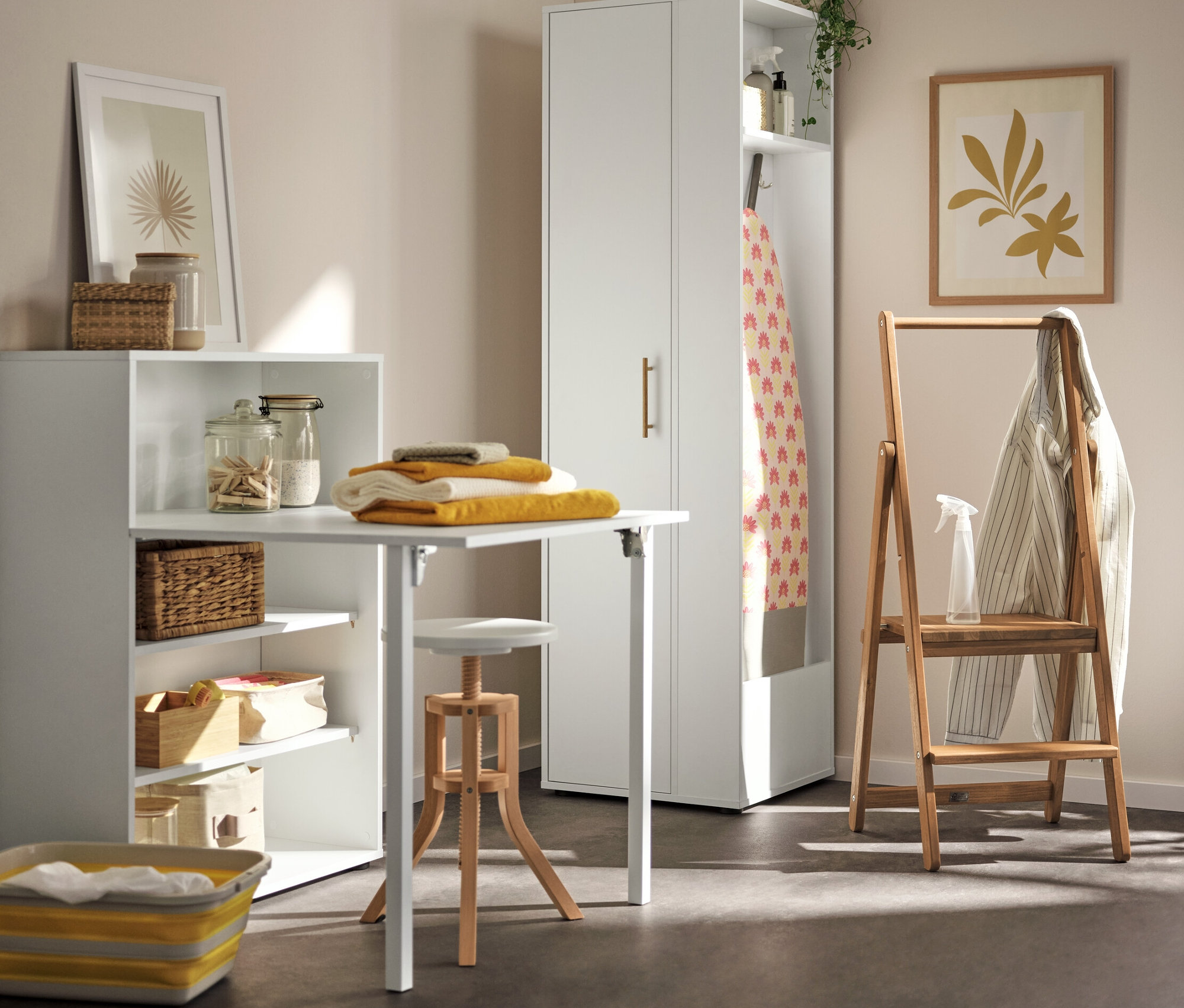 Im Waschraum steht ein Regal mit ausklappbarem Tisch, auf dem gelbe Handtücher liegen. Links davon befindet sich ein Universalschrank mit seitlichem Stauraum. In der Ecke steht eine Trittleiter aus Massivholz.