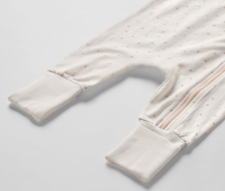Detailansicht eines Baby-Pyjamas mit rosa Punkten und Reißverschluss.