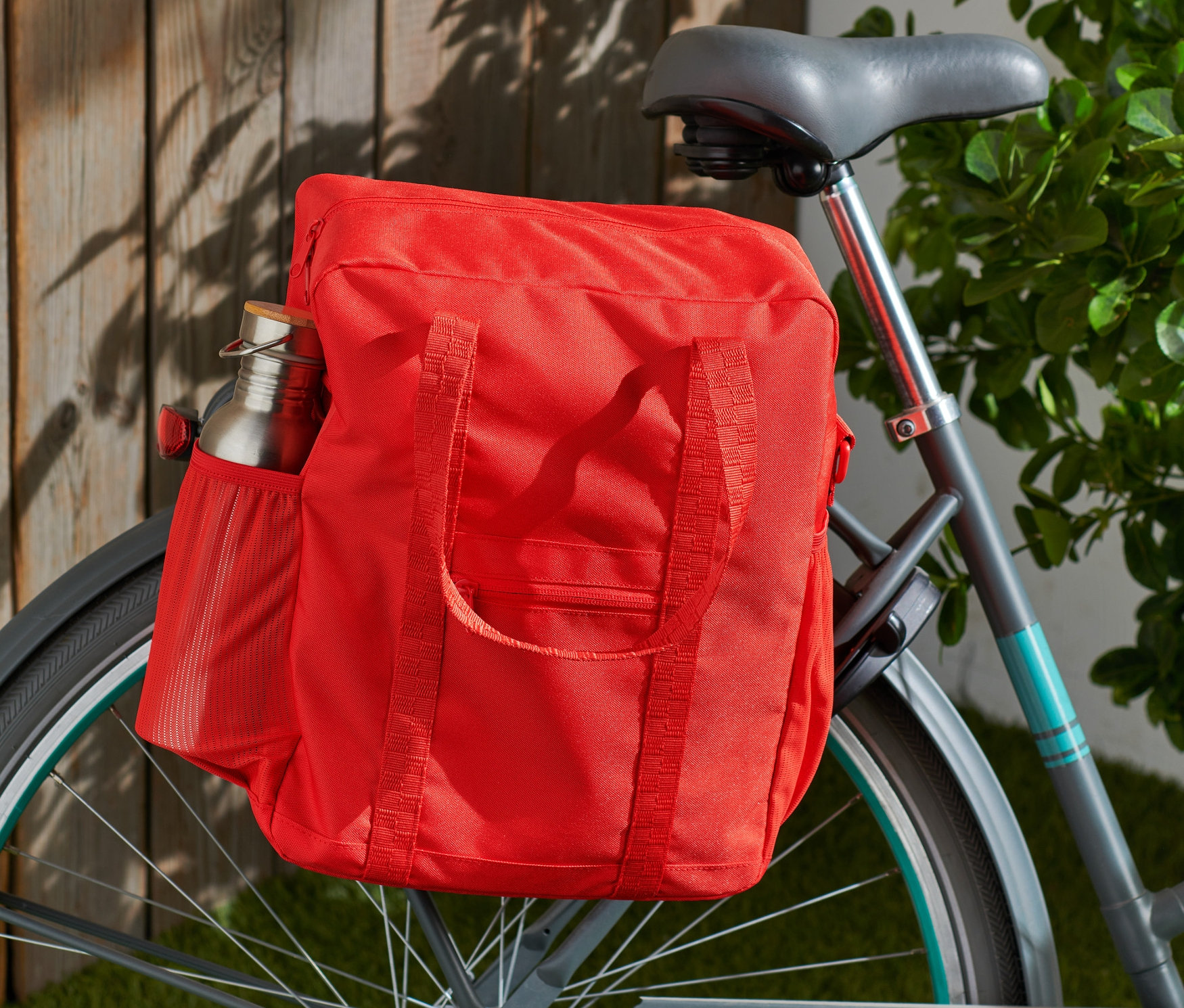 Eine rote Rad-und-Umhängetasche ist an einem Fahrrad befestigt.