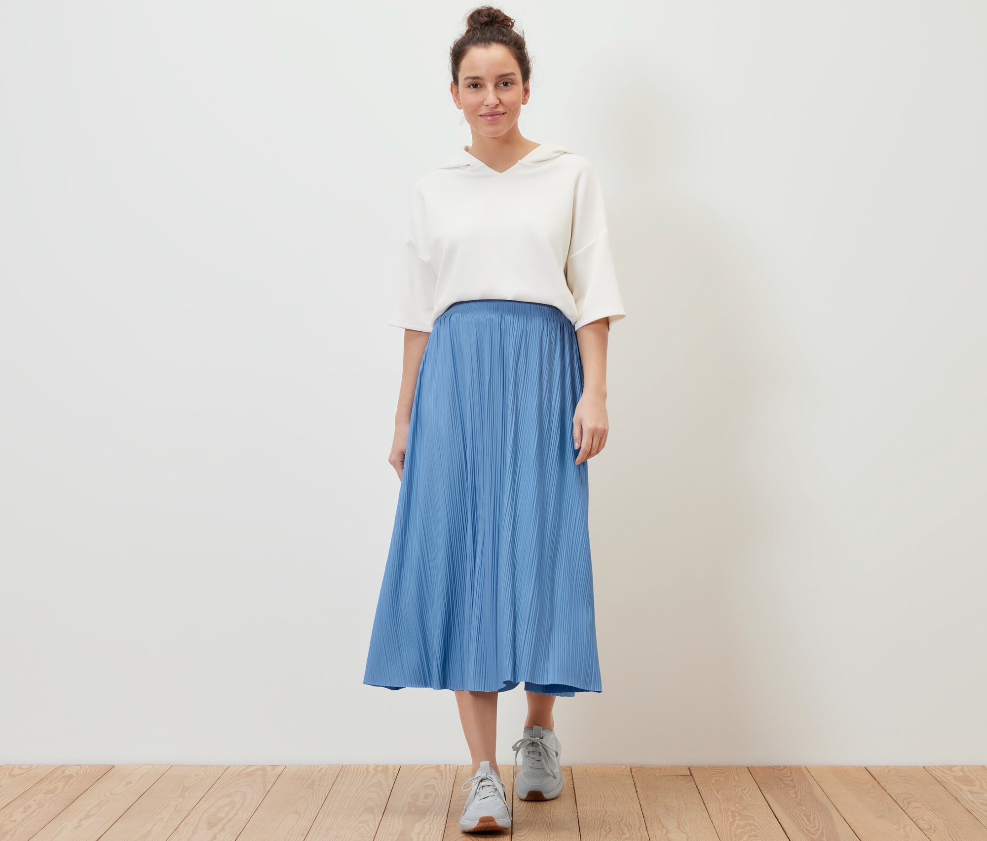 Frau posiert in einem Plisseerock.