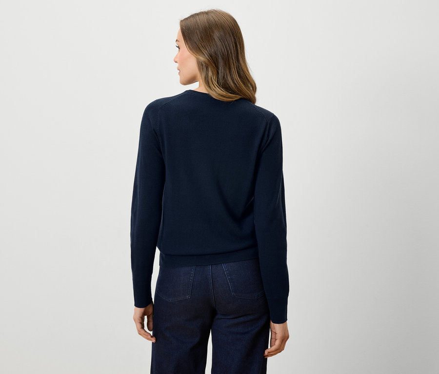 Rückansicht einer Frau in dunkelblauem Pullover und dunklen Jeans.