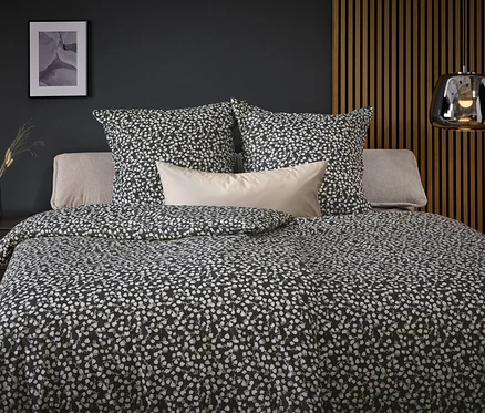 Schwarz-weiß gemusterte Bettwäsche auf einem Bett mit Kissen.