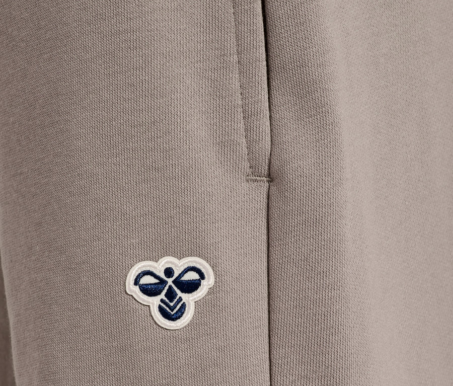 Nahaufnahme einer beigen Jogginghose mit einer aufgenähten Hummel-Biene.