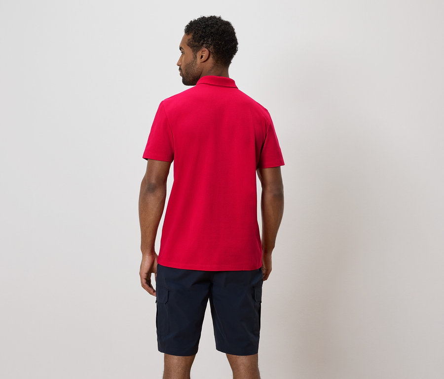 Mann von hinten, mit rotem Poloshirt und blauen Shorts.