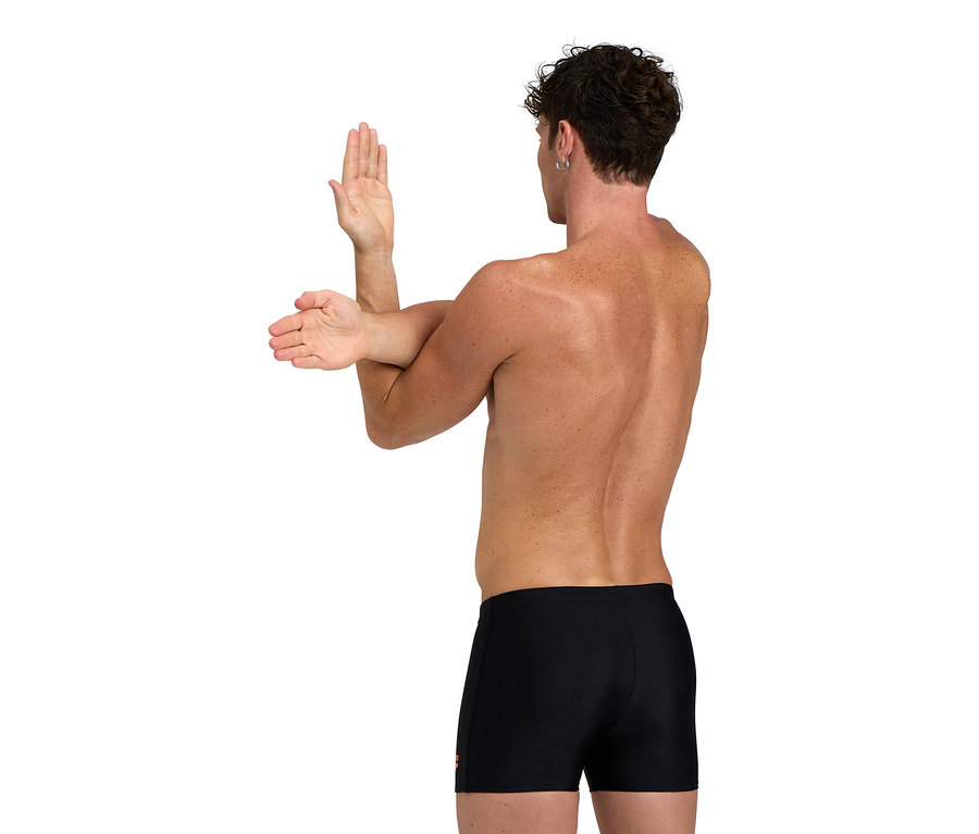 Mann dehnt Arme, trägt schwarze Badehose.