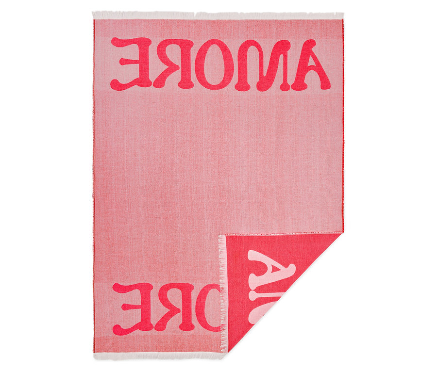 Nahaufnahme einer hellroten Decke mit dem Schriftzug "AJVOKE" in dunklerem Rot, wobei ein Teil der Decke umgeschlagen ist.