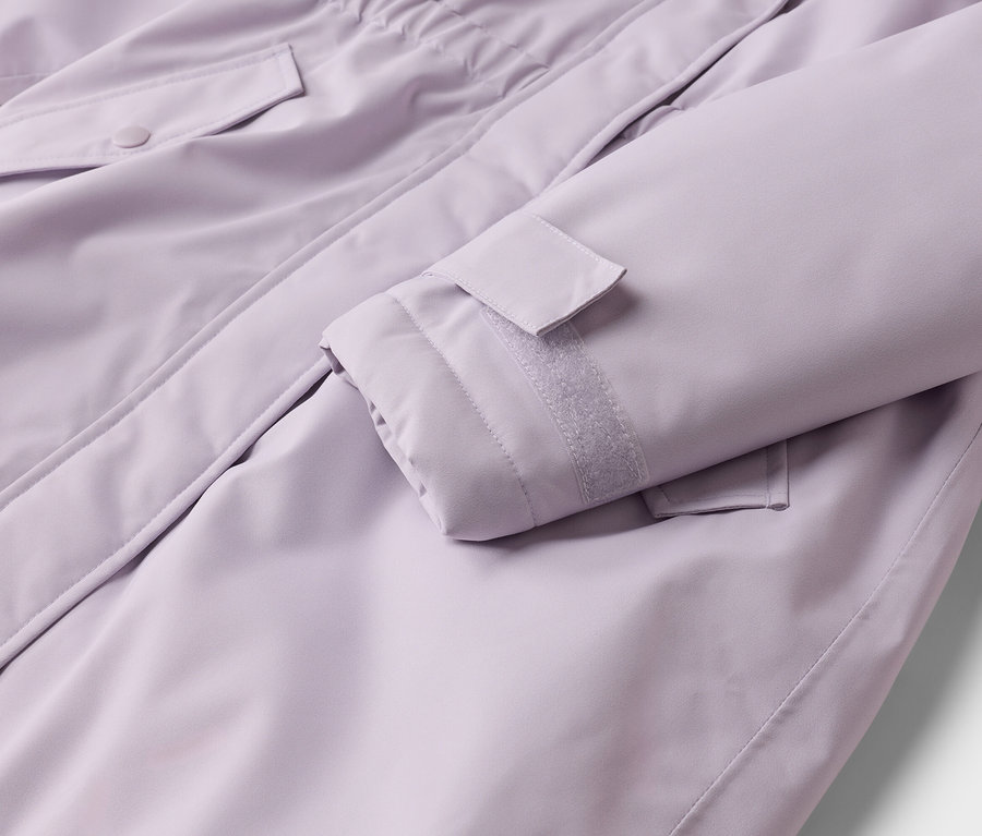 Nahaufnahme einer lila Jacke, die einen Ärmel mit verstellbarer Klettverschlussmanschette und eine Pattentasche mit Knopfverschluss zeigt.