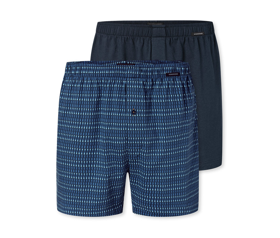 Zwei Herren-Boxershorts, eine blaue mit hellblauen Streifen und eine dunkelblaue, liegen übereinander.