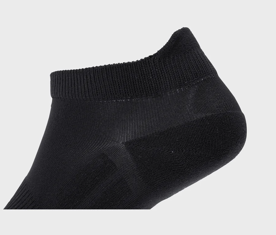 Nahaufnahme einer schwarzen Socke mit geripptem Bündchen und Bereichen aus dünnerem, durchsichtigem Stoff.