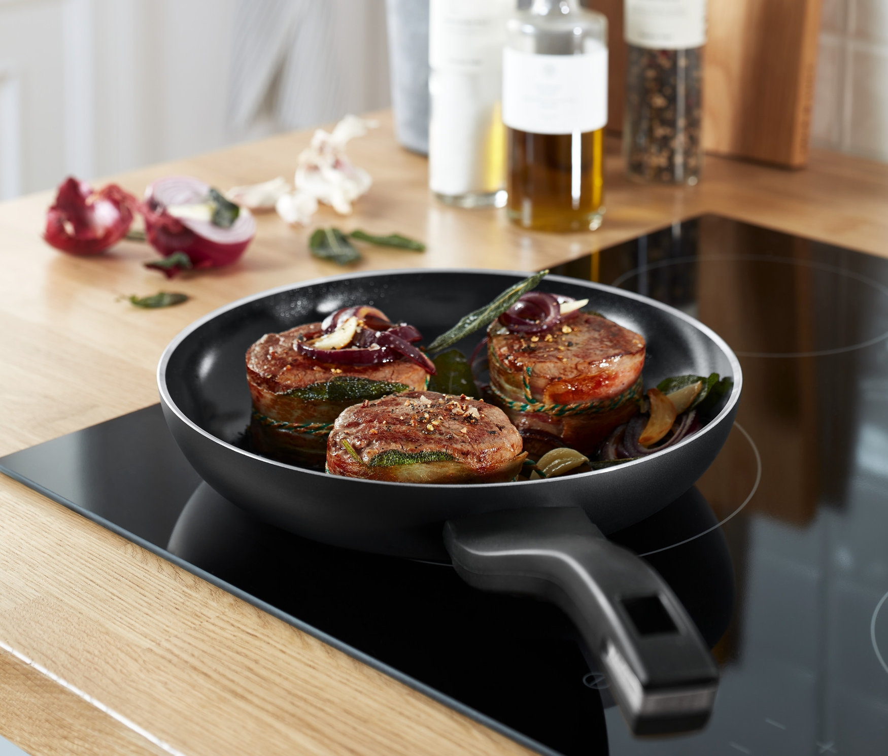 Drei Speiseportionen in der Bratpfanne »Alu Recycled Induction b. green« auf einem Induktionskochfeld.